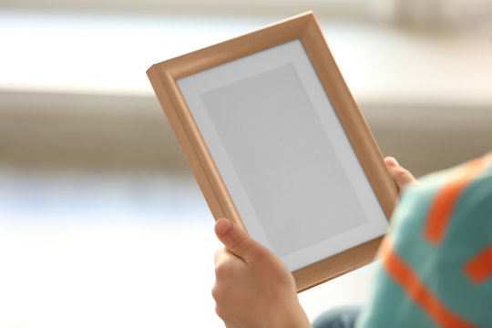 Child's hands holding photo frame on light background