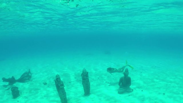 UNDERWATER: Woman swimming around sunken statues sanctuary under the sea