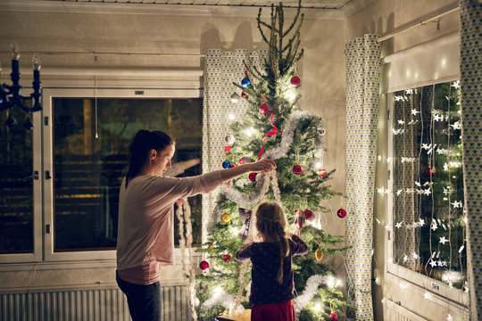 Finland, Mother with daughter (4-5) decorating christmas tree