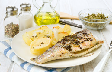 baked sea bass with potatoes in tray