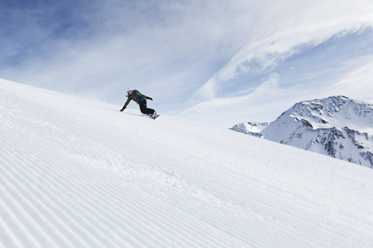 Switzerland, Andermatt, Young woman snowboarding in Alps