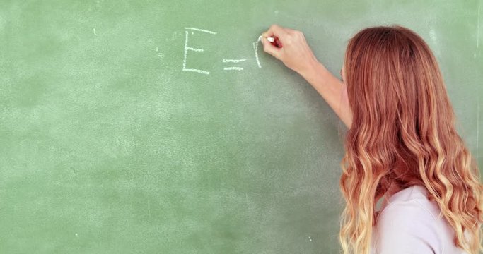 Teacher writing e = mc squared in high quality 4k format
