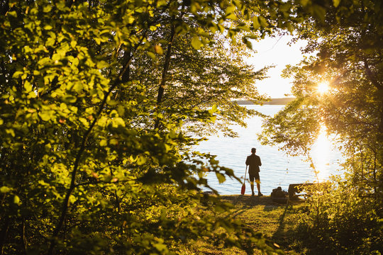 Sweden, Skane, Immeln, Silhouette of man standing with oar at sunset