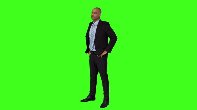 Businessman standing with hands on hips on green screen background