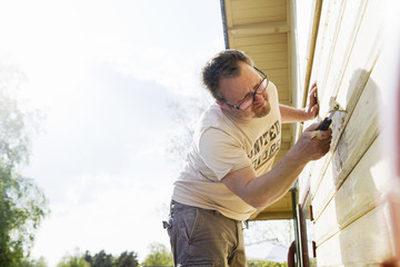 Sweden, Vastra Gotaland, Mid adult man renovating wall of house