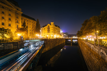 Fototapeta na wymiar Buildings along and train bridge over Wienfluss at night, in Vie
