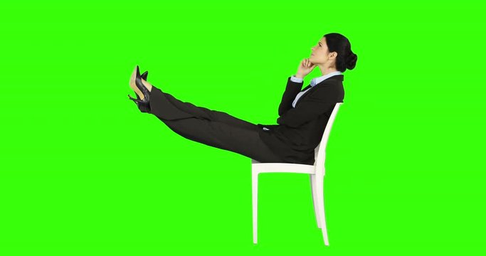Business woman relaxing on a chair with legs up on green screen