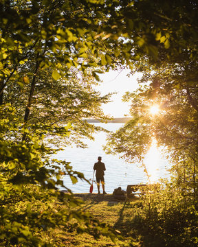 Sweden, Skane, Immeln, Silhouette of man standing with oar at sunset