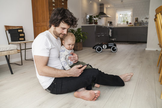 Sweden, Father and son (12-17 months) using smart phone
