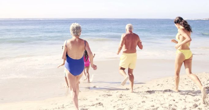 Cute family running in the water on the beach in slow motion