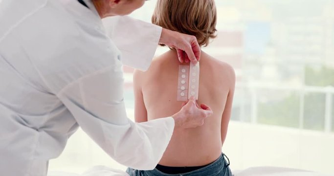 Doctor sticking patch test at her patient in medical office