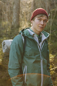 Finland, Esbo, Kvarntrask, Portrait of young man wearing woolly hat and windcheater jacket in forest