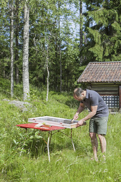 Sweden, Dalarna, Falun, Man scraping off old putty from window frame