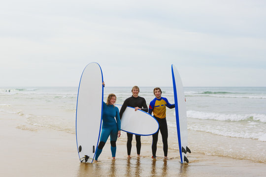 Portrait of smiling young people holding surfboards on beach