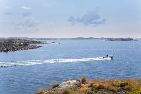 Sweden, Swedish West Coast, Bohuslan, Kyrkesund, Tarneskar, People in boat travelling by coastline