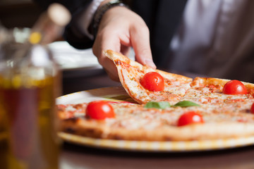 Man at home eating a slice of pizza and social networking with a