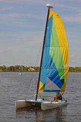 Young woman at the helm of a small sail catamaran on a river in southeast florida