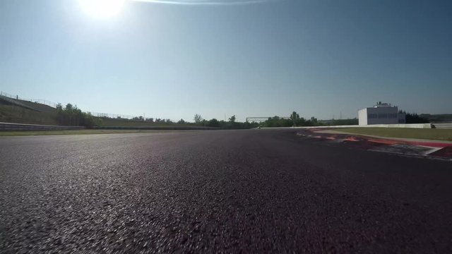 LOW ANGLE VIEW: Race car competing and driving fast on race track lap