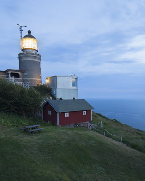Sweden, Skane, Kullaberg, Illuminated lighthouse at dusk