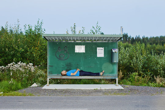 Side view of man sleeping at bus stop