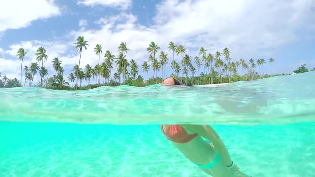 SLOW MOTION: Woman swimming underwater relaxing in tropical island lagoon
