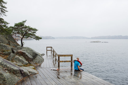 Man sitting on pier and looking at Baltic Sea