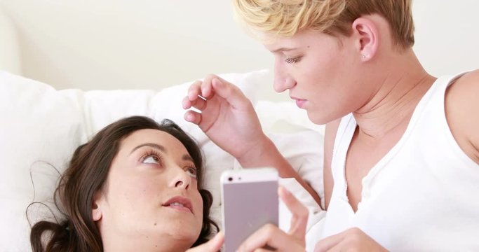 Lesbian couple lying in bed using phone in high quality 4k format