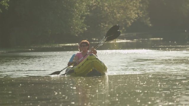 SLOW MOTION: Happy smiling couple kayaking along the river