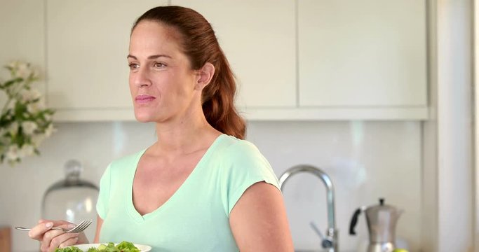 Pregnant woman eating salad in kichen
