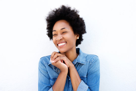 Delighted woman smiling by white wall