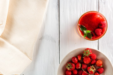 glass of berry smoothie, plate with raspberries and strawberries