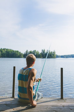 Finland, Pirkanmaa, Salmentaka, Lake Palkanevesi, Young man fishing off lake pier