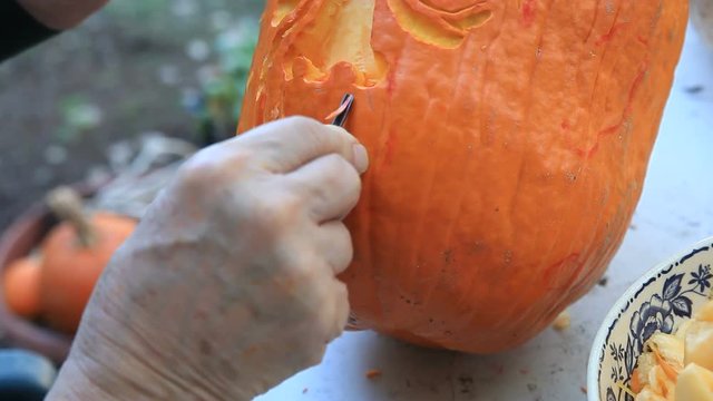 Closeup man carves Halloween pumpkin
