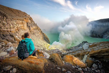 Woman with backpacker enjoying view at top volcano Ijen.