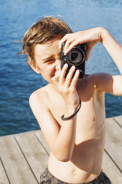 Sweden, Uppland, Runmaro, Barrskar, Portrait of boy (6-7) photographing on jetty
