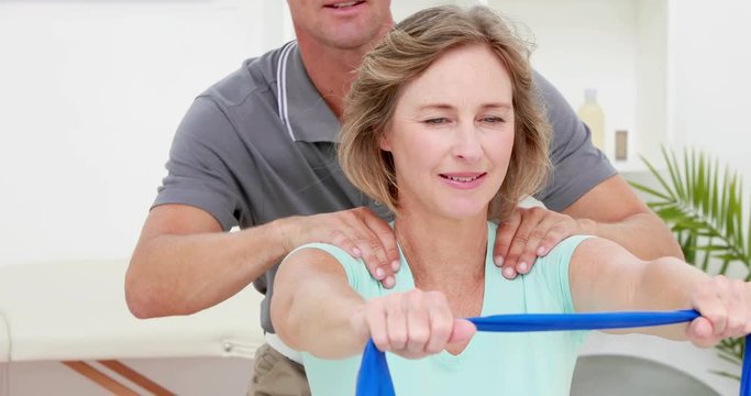 Physiotherapist checking patient stretching resistance band