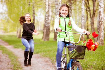 happy mother teaches his daughter to ride a bike. A mother is glad to successes of daughter