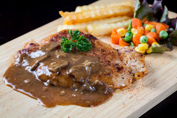 Close up steak pork with mushroom sauce, french fries and salad