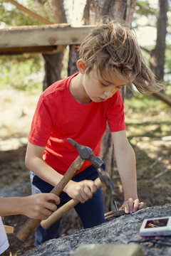 Sweden, Uppland, Runmaro, Barrskar, Boy (6-7) pounding with hammer