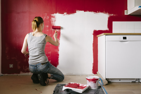 Rear view of woman painting wall in kitchen
