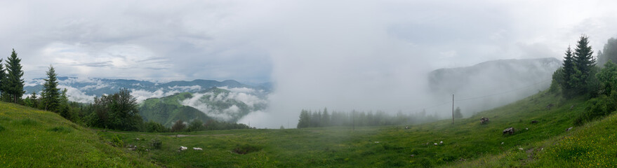Naklejka na ściany i meble Clouds and rain in a mountain valley landscape panorama
