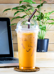 Thai ice tea with milk in plastic cup on wood desk