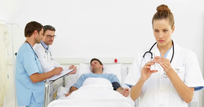 Doctors speaking with sick patient in bed while nurse prepares injection