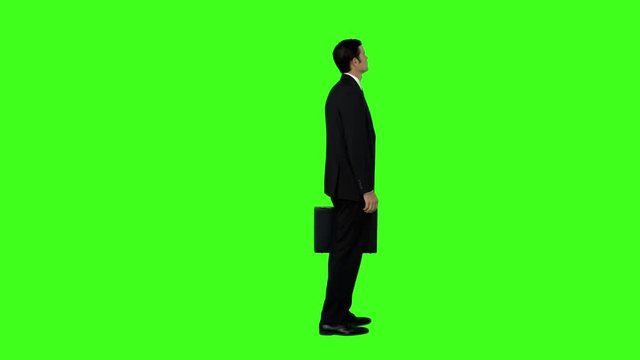 Businessman standing with his briefcase on green screen background