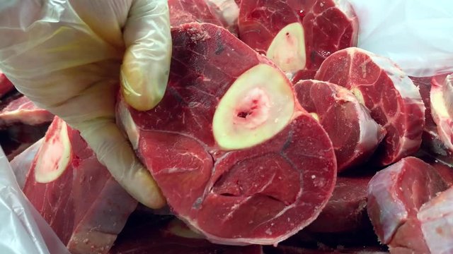 Chef is picking up raw osso buco meat from a box full of fresh veal meat