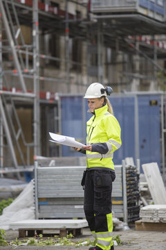 Construction worker looking at blueprints while standing at construction site