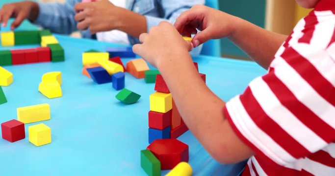 Cute little boys playing with building blocks at table
