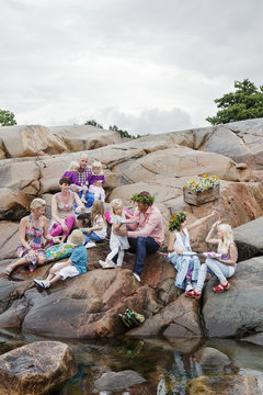Sweden, Uppland, Roslagen, Big family having picnic on rocks at seaside