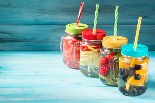 Assorted detox water cocktails in glass jars on wooden background
