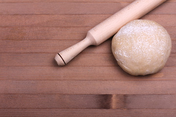 the dough with a rolling pin on brown wooden  background